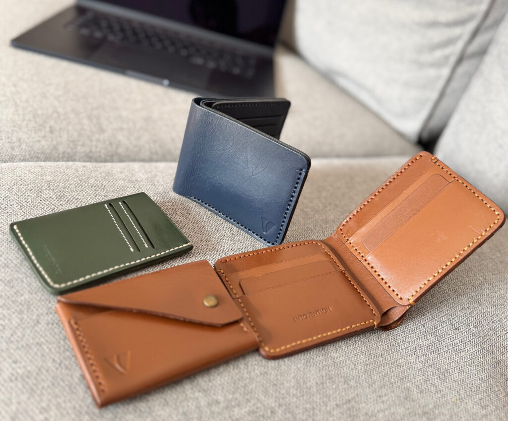 Assorted Intovention wallets and card holder in cognac, green, and navy leather.